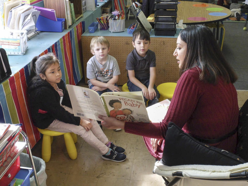 FILE - From left, Cynthia Lopez, Michael Neal and Christian Candelaria listen as Dupont Elementary School teacher Sonal Patel reads to them on Nov. 22, 2019, in Chattanooga, Tenn. For decades, there has been a clash between two schools of thought on how to best teach children to read, with passionate backers on each side of the so-called reading wars. But the approach gaining momentum lately in American classrooms is the so-called science of reading. (Tim Barber/Chattanooga Times Free Press via AP, File)
