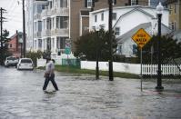 A man crosses a flooded street in Ocean City, Maryland, on October 3, 2015 as coastal flooding warnings are issued along the US east coast as heavy rains, partly fueled by Hurricane Joaquin, continue to fall on the area
