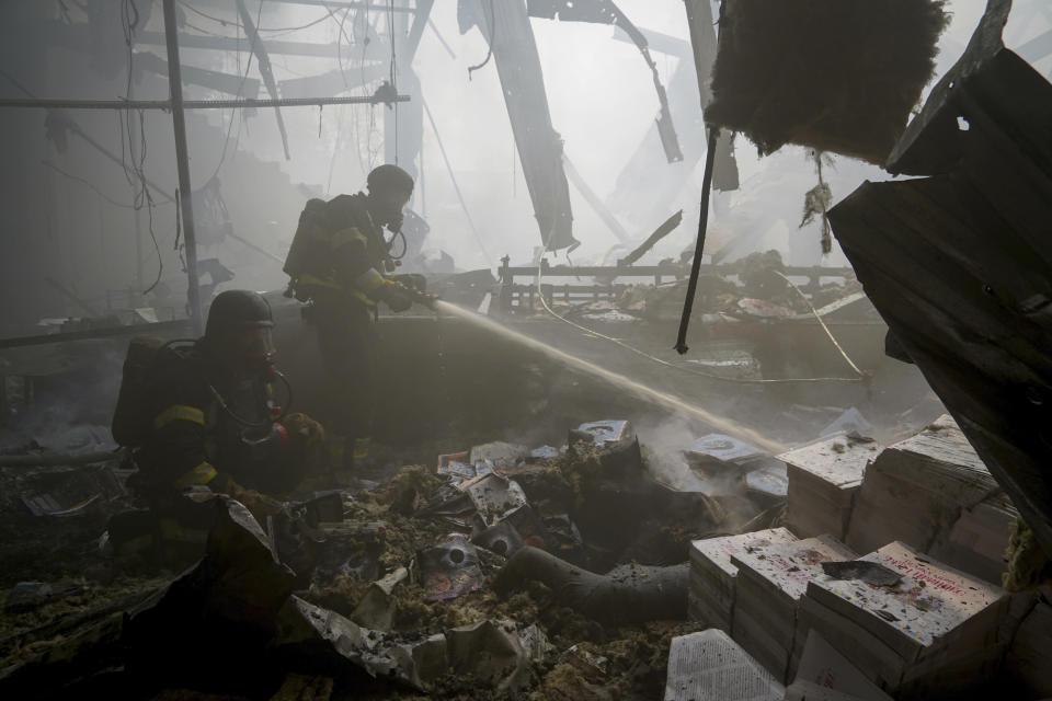 Firefighters hose down a fire as a lifeless body lies under the rubble after a Russian missile hit a large printing house in Kharkiv, Ukraine, Thursday, May 23, 2024. Russian missiles slammed into Ukraine’s second-largest city in the northeast of the country and killed at least seven civilians early Thursday, officials said, as Kyiv’s army labored to hold off an intense cross-border offensive by the Kremlin’s larger and better-equipped forces. (AP Photo/Andrii Marienko)