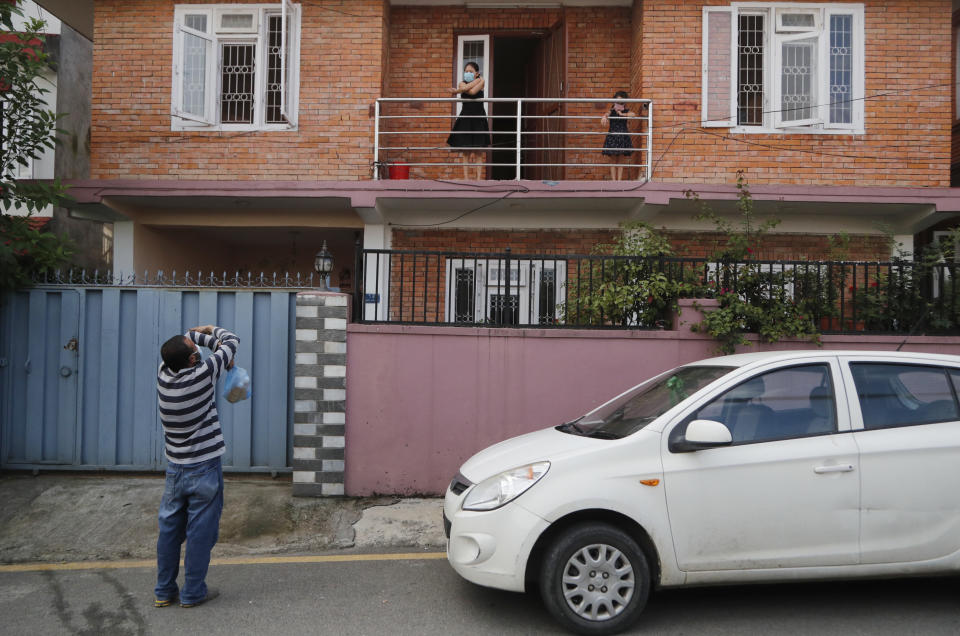 Pharmacist Bikram Bhadel gives air hugs to his daughters from outside his house in Kathmandu, Nepal, Monday, Aug. 31, 2020. Bhadel and his friend Indra Kumar Newar, a taxi driver, have teamed up to feed hot, tasty and nutritious food three times a day to more than 200 COVID-19 patients, doctors, nurses and workers at one of Nepal’s largest hospitals. The two friends have taken their own money and donations and put it to use buying groceries, renting a kitchen and paying helpers to provide the meals. (AP Photo/Niranjan Shrestha)