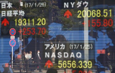 Pedestrians are reflected on an electronic board showing Japan's Nikkei average (top L), the Dow Jones average (top R) and the stock averages of other countries outside a brokerage in Tokyo, Japan, January 26, 2017. REUTERS/Kim Kyung-Hoon