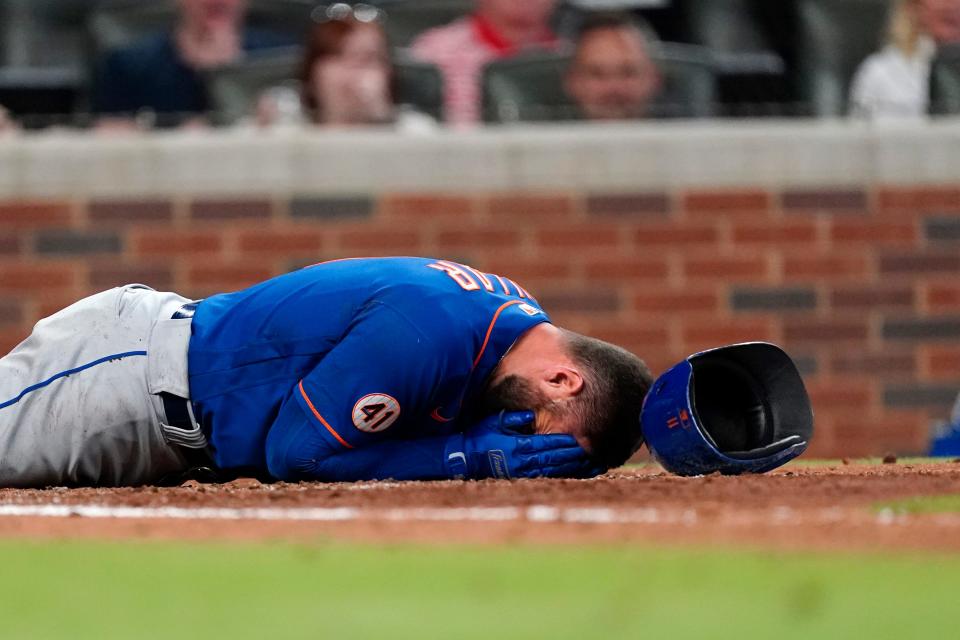 The New York Mets' Kevin Pillar lies on the ground after being hit in the face with a pitch from Atlanta Braves pitcher Jacob Webb in the seventh inning.