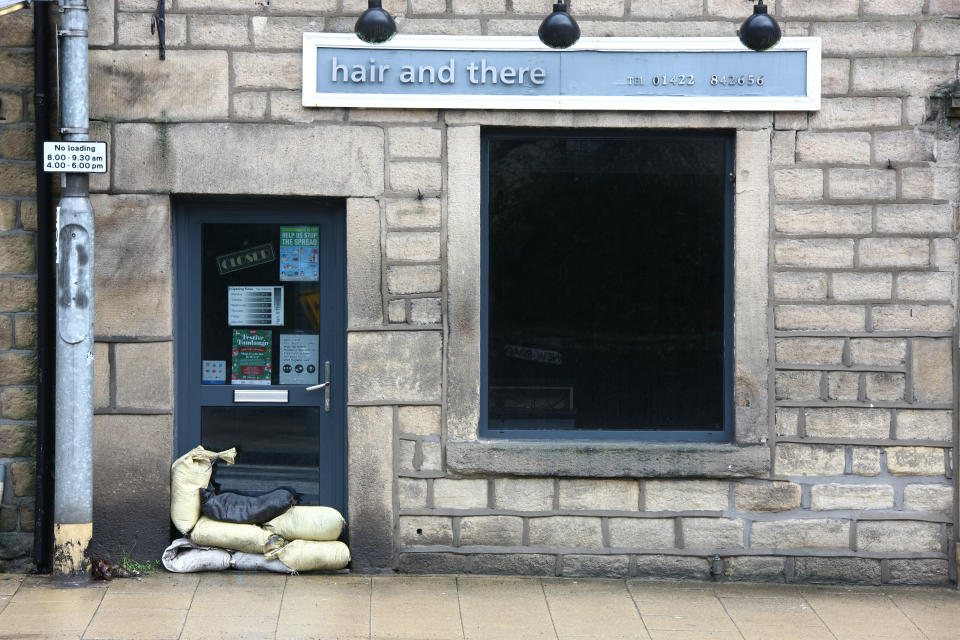 HEBDEN BRIDGE, WEST YORKSHIRE, UNITED KINGDOM - 2021/01/19: Sandbags are piled up against the door of a hair salon in Hebden Bridge on Tuesday morning as residents prepare for Storm Christoph. Residents are preparing for potential flooding as heavy rain from Storm Christoph is expected to fall onto ground which is already saturated from recent snow. (Photo by Adam Vaughan/SOPA Images/LightRocket via Getty Images)