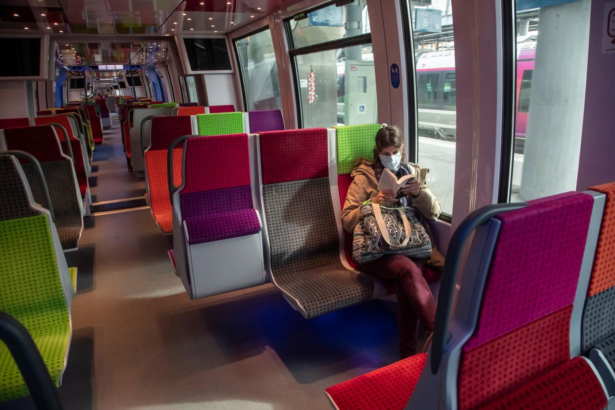 A commuter wears a mask to protect against the spread of the coronavirus reads a book as she sits in a train in Saint Cloud, west of Paris, Tuesday, April 7, 2020.