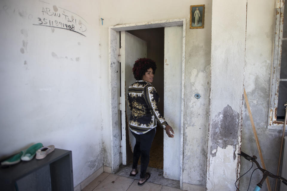 In this photo taken on Monday, April 27, 2020, Mary Sado Ofori, 33 year-old from Nigeria, walks into her her home in Castel Volturno, near Naples, Southern Italy. Mary Sado Ofori has three children, including a little baby. Normally she works as a hairdresser doing weaves and braids for other women, bringing in a little money. Now she cannot work. They are known as “the invisibles,” the undocumented African migrants who, even before the coronavirus outbreak plunged Italy into crisis, barely scraped by as day laborers, prostitutes and seasonal farm hands. Locked down for two months in their overcrowded apartments, their hand-to-mouth existence has grown even more precarious with no work, no food and no hope. (AP Photo/Alessandra Tarantino)
