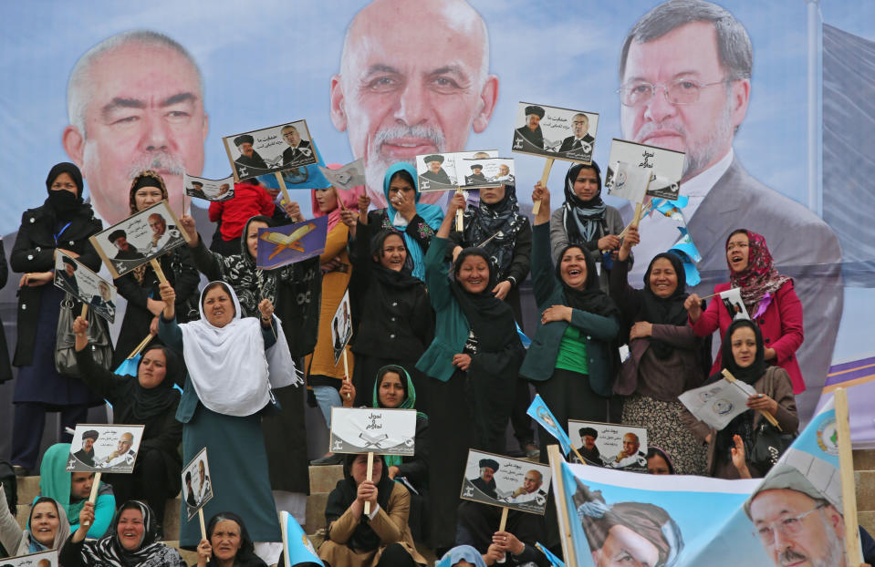 In this photo taken on Tuesday, April 1, 2014, female supporters of Afghan presidential candidate Ashraf Ghani Ahmadzai listen to his speech during a campaign rally in Kabul, Afghanistan. Two Afghan women shrouded in black emerged from the campaign rally with bundles of sticks _ pieces of torn posters still attached. They needed firewood to heat their home more than pictures of the presidential hopeful.(AP Photo/Massoud Hossaini)