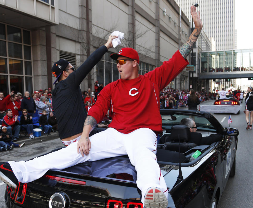 Cincinnati Reds starting pitcher Mat Latos rides on the back of a car during the annual opening day parade, Monday, March 31, 2014, in Cincinnati. The Cincinnati Reds play the St. Louis Cardinals. (AP Photo/David Kohl)