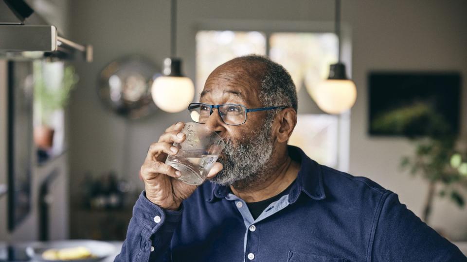 contemplative senior man drinking water at home