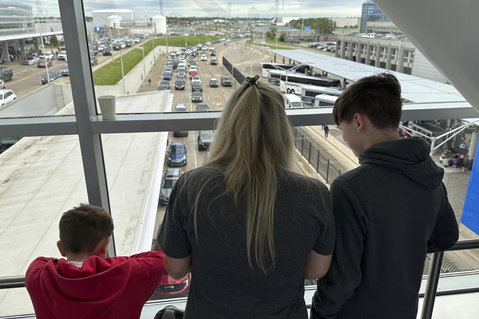 Mitzi Hale and her three sons look out a window at backed-up traffic due to the closure of Detroit Metropolitan Airport's McNamara Terminal on Thursday, Aug. 24, 2023, in Romulus, Mich. A flight originating from McNamara that was scheduled to take Hale and her boys to Florida for a vacation was delayed. Parts of Michigan received more than 5 inches of rain, which flooded tunnels leading to Detroit's main airport. (AP Photo/Mike Householder)