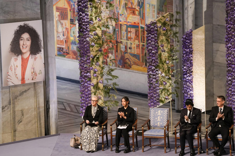 Ali, second right, and Kiana Rahmani, second left, attend the awarding of the Nobel Peace Prize for 2023 to their mother, imprisoned Iranian activist Narges Mohammadi, shown on the screen, in Oslo City Hall, Oslo, Norway, Sunday, Dec. 10, 2023. The children of Narges Mohammadi will accept this year’s Nobel Peace Prize on her behalf. Mohammadi is renowned for campaigning for women’s rights and democracy in her country. (Fredrik Varfjell/NTB via AP)