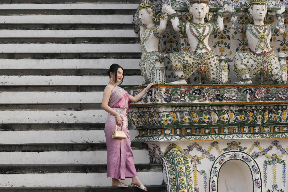 A Chinese tourist in traditional Thai dress poses for a photograph at Wat Arun or the "Temple of Dawn" in Bangkok, Thailand on Jan. 12, 2023. A hoped-for boom in Chinese tourism in Asia over next week’s Lunar New Year holidays looks set to be more of a blip as most travelers opt to stay inside China if they go anywhere. (AP Photo/Sakchai Lalit)