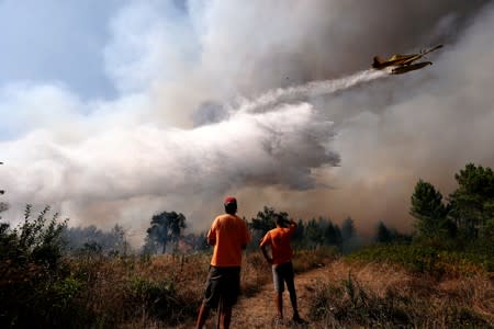A firefighting plane dumps water on a forest fire next to the village of Vila de Rei