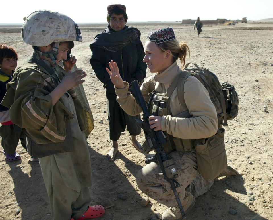 BOLDOC, AFGHANISTAN - NOVEMBER 23: (SPAIN OUT, FRANCE OUT, AFP OUT) Lance Corporal Riane Donoho, 21, US Marine with the FET (Female Engagement Team) 1st Battalion 8th Marines, Regimental Combat team II trades hats with an Afghan boy during a village medical outreach November 23, 2010 in Boldoc, in Helmand province , Afghanistan. There are 48 women presently working along the volatile front lines of the war in Afghanistan deployed as the second Female Engagement team participating in a more active role, gaining access where men can't. The women, many who volunteer for the 6.5 month deployment take a 10 week course at Camp Pendleton in California where they are trained for any possible situation, including learning Afghan customs and basic Pashtun language. (Photo by Paula Bronstein/Getty Images)