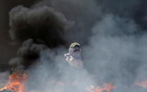 <p>A female Palestinian demonstrator stands amid smoke during a protest against the U.S. Embassy’s move to Jerusalem and ahead of the 70th anniversary of Nakba, at the Israel-Gaza border east of Gaza City on May 14, 2018. (Photo: Mohammed Salem/Reuters) </p>