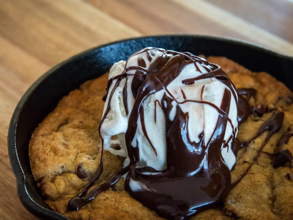 chocolate chip cookie baked in a cast iron skillet topped with vanilla ice cream and chocolate sauce