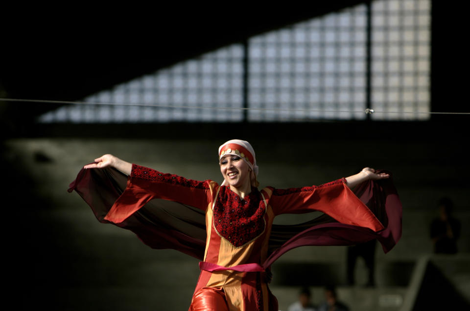 FILE - In this April 29, 2007 file photo, a Palestinian woman wearing a Palestinian dress with traditional embroidery performs a folk dance known as Debka, during a folk festival in the West Bank city of Ramallah. The thobe, a brightly embroidered robe for women, has long been a staple of Palestinian life, sewn by village women and worn at weddings and parties. Now it’s gaining prominence as a softer symbol of Palestinian nationalism, competing with the classic keffiyeh. (AP Photo/Muhammed Muheisen, File)