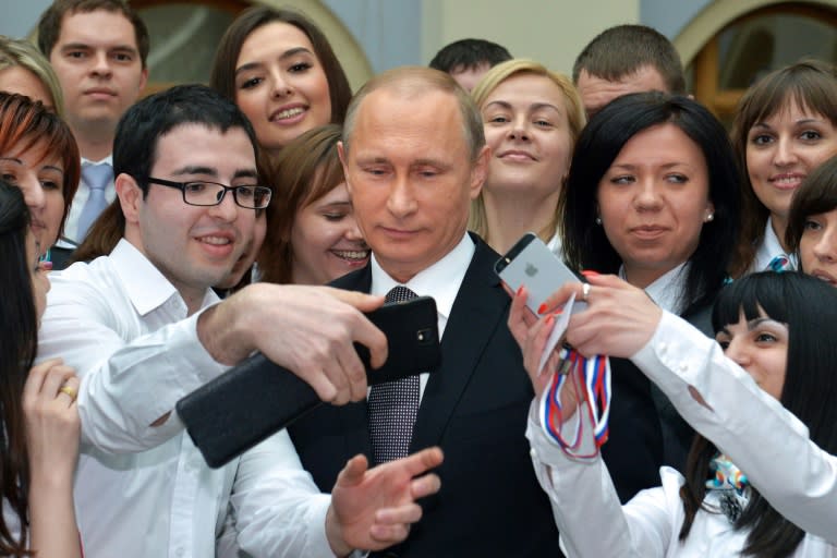 A man takes a selfie with Russian President Vladimir Putin (C) shortly after his annual televised phone-in with the nation in central Moscow on April 16, 2015