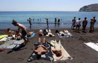 Tourists sunbathe on the Red Beach on the Greek island of Santorini, Greece, July 2, 2015. REUTERS/Cathal McNaughton/Files