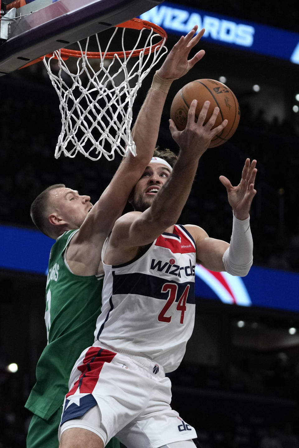 Washington Wizards forward Corey Kispert (24) is fouled by Boston Celtics center Kristaps Porzingis, left, as he goes to the basket during the first half of an NBA basketball game Monday, Oct. 30, 2023, in Washington. (AP Photo/Mark Schiefelbein)