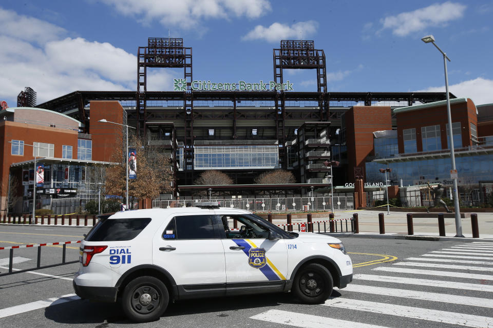 FILE - In this March 24, 2020, file photo, a Police vehicle blocks a street near Citizens Bank Park, home of the Philadelphia Phillies baseball team, in Philadelphia. On MLB’s opening day, ballparks will be empty with the start of the season on hold because of the coronavirus pandemic. (AP Photo/Matt Slocum, File)