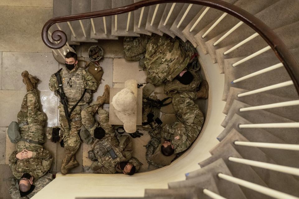 Men in uniform sleep on the ground.