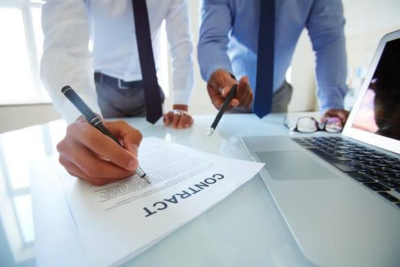 Two men in suits looking over a contract.