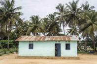 A woman stands outside her home in her village of Tshiende, which has been impacted by the pollution caused by oil drilling, in Moanda, Democratic Republic of the Congo, Saturday, Dec. 23, 2023. (AP Photo/Mosa'ab Elshamy)