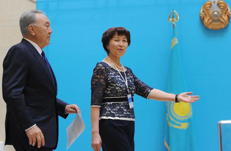 An electoral commission official invites Kazakh President Nursultan Nazarbayev (L) to cast his ballot at a polling station in the capital Astana on April 26, 2015