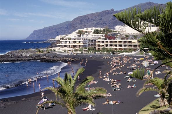 SPAIN Canary Islands Tenerife Playa de la Arena near Los Gigantes with sunbathers on black sandy beach and apartments in the dis