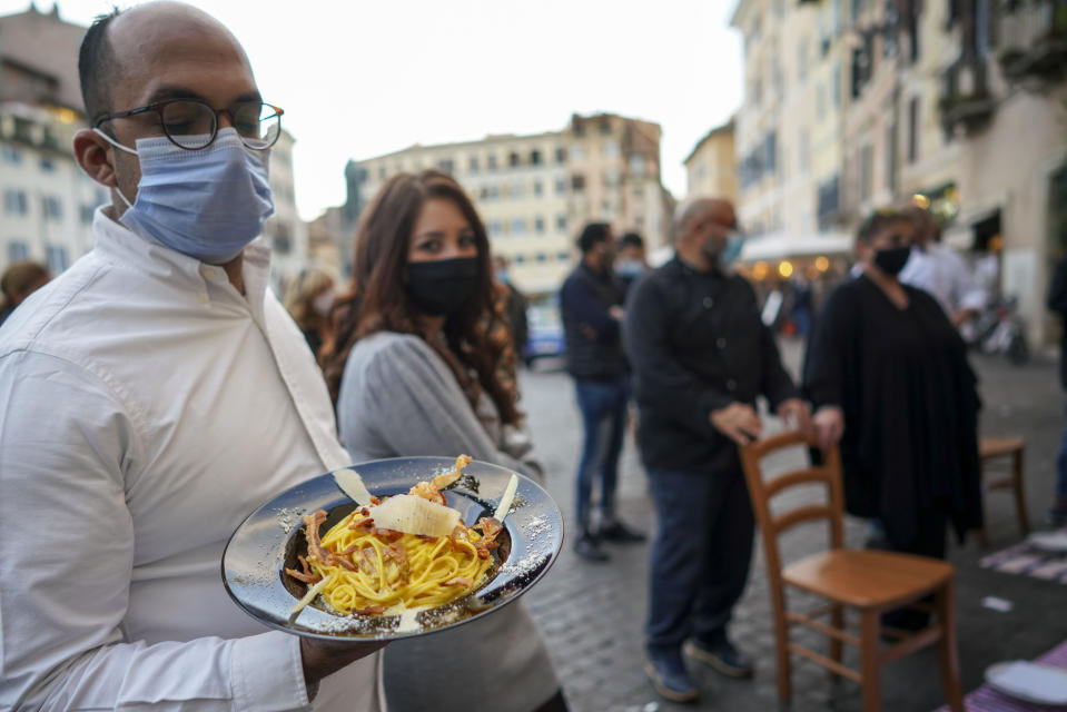 A man holds a plate of "Carbonara" spaghetti as restaurant owners protest against the government restriction measures to curb the spread of COVID-19, closing restaurants at night, in Rome, Wednesday, Oct. 28, 2020. For at least the next month cafes and restaurants must shut down in early evenings, under a decree signed on Sunday by Italian Premier Giuseppe Conte. (AP Photo/Andrew Medichini)