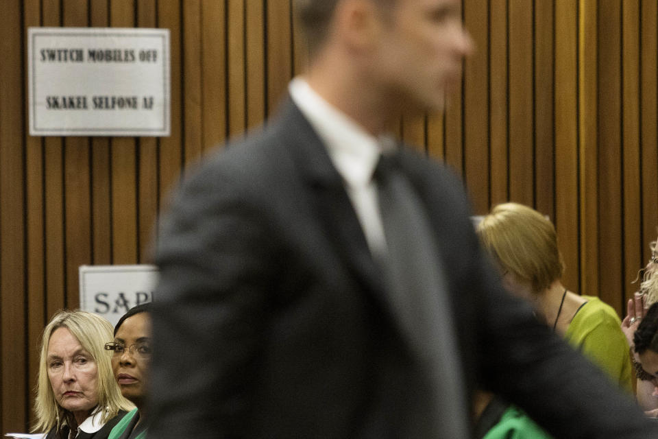 June Steenkamp, bottom left, mother of the late Reeva Steenkamp, sits behind Oscar Pistorius, front, as they wait for the proceedings of his murder trial to begin in court in Pretoria, South Africa, Tuesday, March 18, 2014. Pistorius is on trial for the murder of his girlfriend Reeva Steenkamp on Valentines Day, 2013. (AP Photo/Marco Longari, Pool)