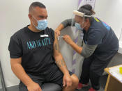 In this photo released by New Zealand Ministry of Health, Aaron Te Moananua, left, receives a dose of the Pfizer COVID-19 vaccine in Auckland, New Zealand, Tuesday, March 9, 2021. New Zealand has opened its first large vaccination clinic as it scales up efforts to protect people from the coronavirus. (New Zealand Ministry of Health via AP)