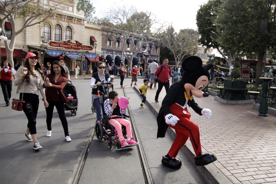 FILE - Visitors follow Mickey Mouse for photos at Disneyland on Jan. 22, 2015, in Anaheim, Calif. A group of performers who help bring Disney's beloved characters to life at the company's California theme parks are forming a union. While most workers at Disneyland and Disney California Adventure already have unions, these roughly 1,700 performers do not, including those who play Mickey Mouse and other iconic characters in meet-and-greets with guests and parades. (AP Photo/Jae C. Hong, File)