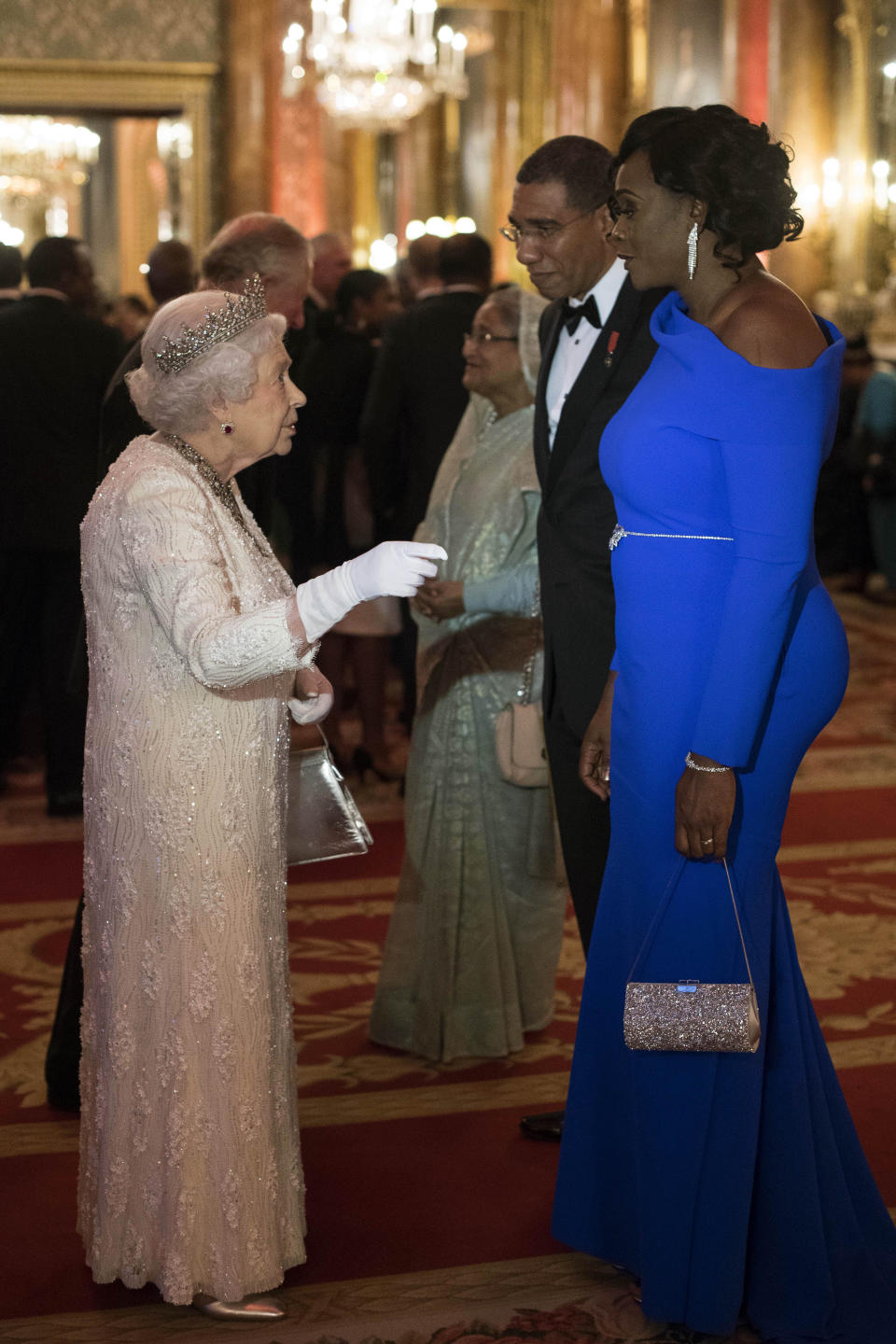 FILE - Britain's Queen Elizabeth II, left, greets Andrew Holness, Prime Minister of Jamaica, and his wife Juliet in the Blue Drawing Room at Buckingham Palace as the Queen hosts a dinner during the Commonwealth Heads of Government Meeting, in London, Thursday April 19, 2018. After seven decades on the throne, Queen Elizabeth II is widely viewed in the U.K. as a rock in turbulent times. But in Britain’s former colonies, many see her as an anchor to an imperial past whose damage still lingers. (Victoria Jones/Pool Photo via AP, File)