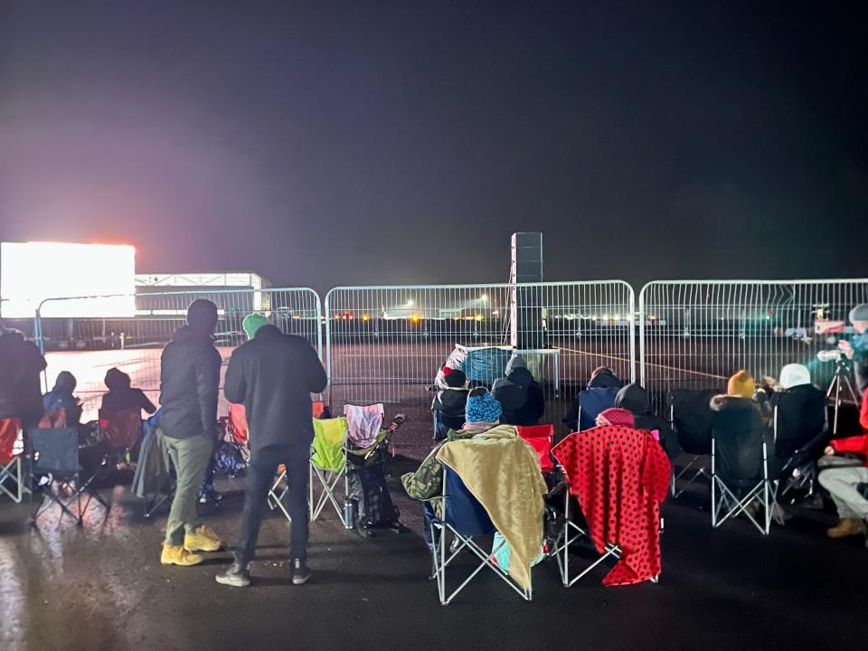 People set up chairs at fence at Spaceport Cornwall