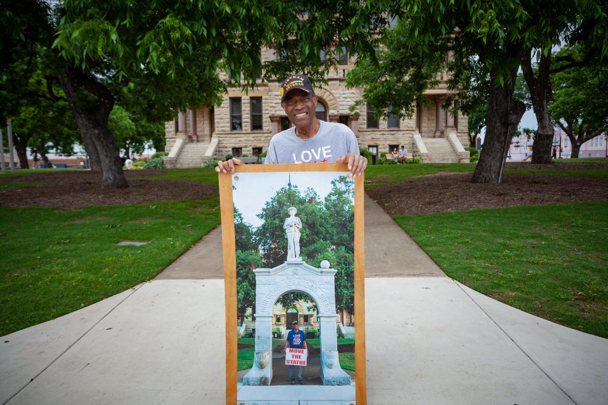 A man displays an image of himself protesting at the foot of a Confederate monument.