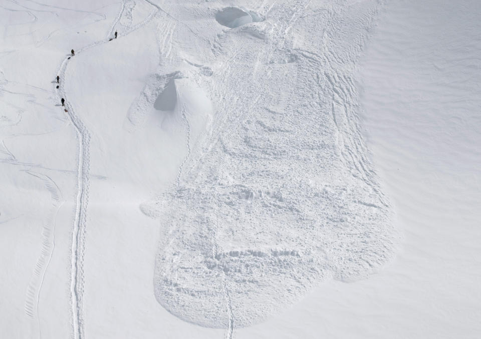 In this Friday, June 15, 2012 photo provided by the National Park Service, climbers hike through the area where an avalanche swept a Japanese climbing team off a hill during their descent from Alaska's Mount McKinley. U.S. National Park Service officials say five people were traveling as a one rope team early Thursday morning as part of a Miyagi Workers Alpine Federation expedition on the Alaska mountain. The NPS said Hitoshi Ogi, 69, survived after falling 60 feet (18 meters) into a crevasse. He was able to climb out. The other four tumbled into the avalanche debris and haven't been seen since. (AP Photo/National Park Service, Kevin Wright)