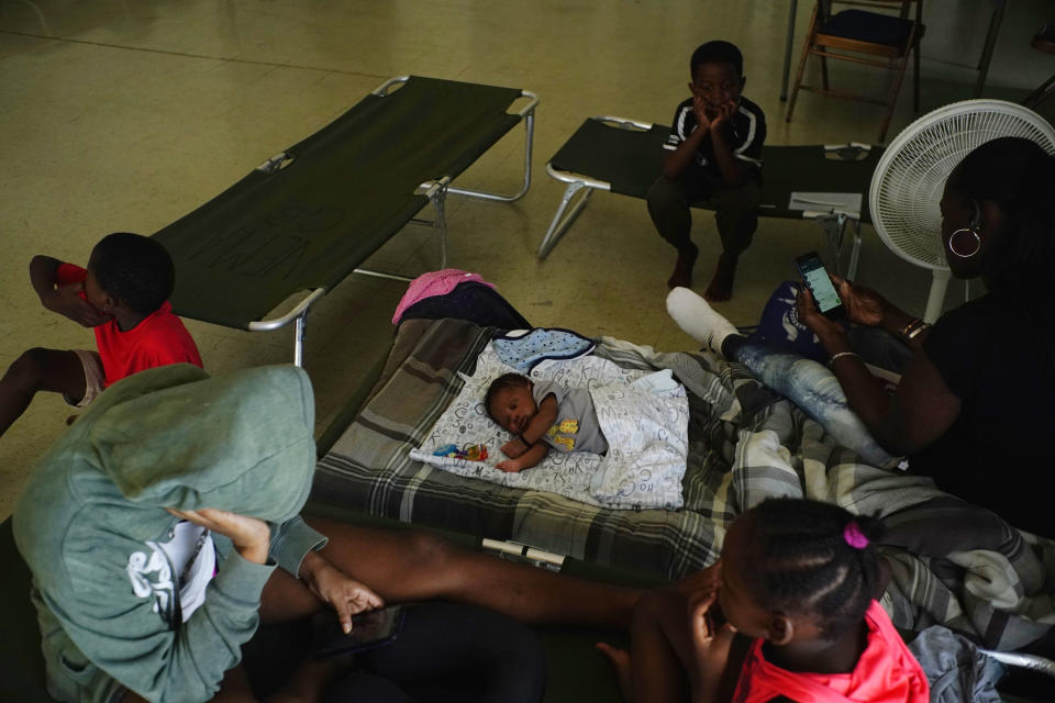 Anastacia Makey, 43, far right, looks at her phone as she and her family sits on cots with other residents inside a church that was opened up as a shelter as they wait out Hurricane Dorian in Freeport on Grand Bahama, Bahamas, Sunday, Sept. 1, 2019. Hurricane Dorian intensified yet again Sunday as it closed in on the northern Bahamas, threatening to batter islands with Category 5-strength winds, pounding waves and torrential rain. (AP Photo/Ramon Espinosa)