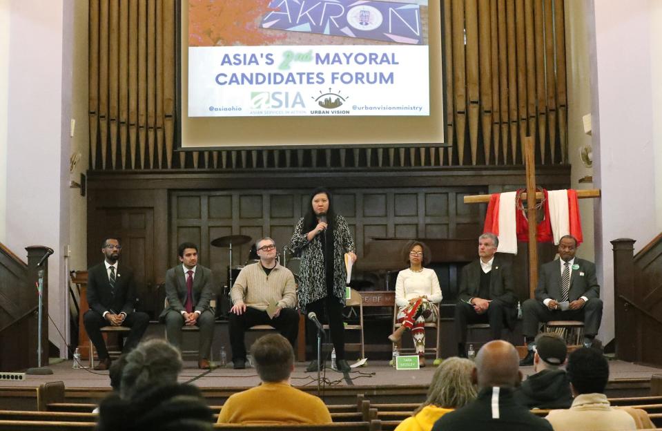 Elaine Tso, ASIA's CEO and moderator, welcomes  the audience  to ASIA's 2nd Mayoral Candidate Forum at Urban Vision in Akron on Saturday. Mayoral candidates, from left, Mark Greer, Shammas Malik, Keith Mills, Tara Mosley, Jeff Wilhite and Marco Sommerville listen to Tso.