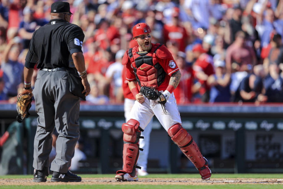 Cincinnati Reds' Tucker Barnhart, right, reacts after tagging out Atlanta Braves' Guillermo Heredia at home plate to end the sixth inning of a baseball game in Cincinnati, Saturday, June 26, 2021. (AP Photo/Aaron Doster)