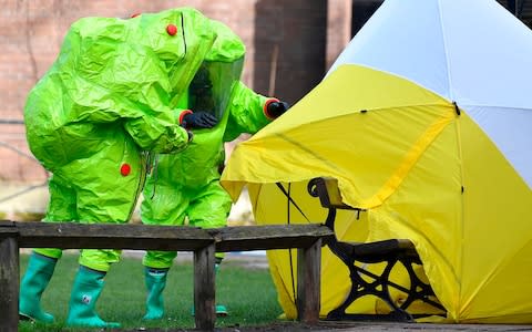 Members of the emergency services in green biohazard encapsulated suits afix a tent over the bench on which the Skripals were found - Credit: BEN STANSALL /AFP