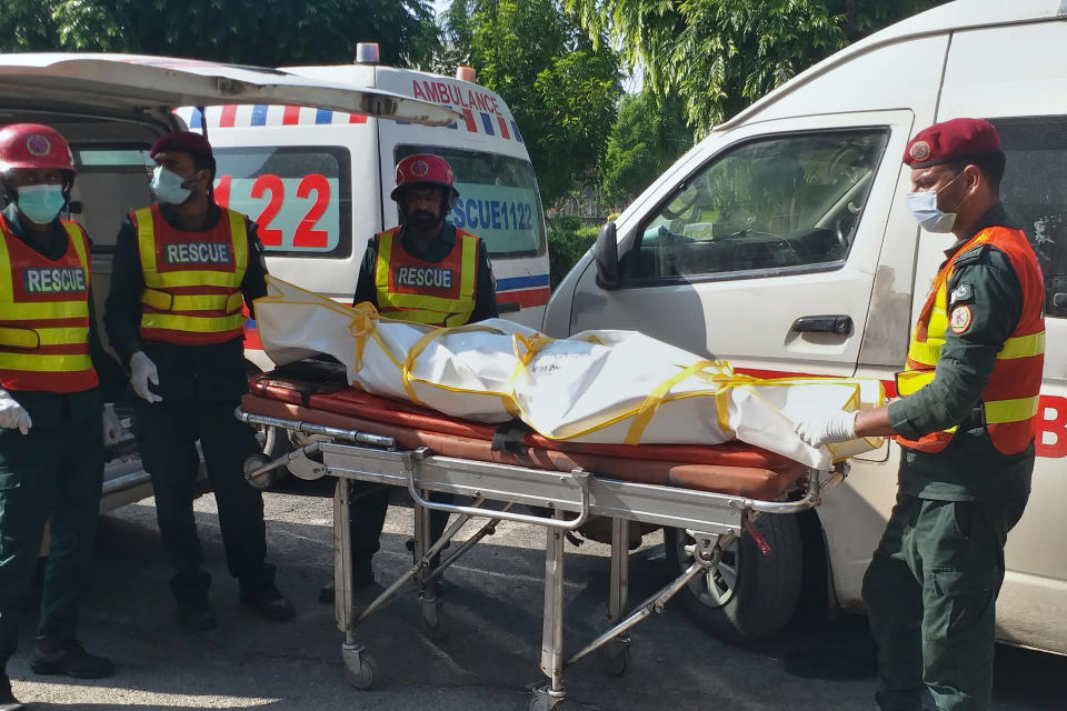 Rescue workers transport the body of a bus accident victim to a hospital in Multan, Pakistan, Tuesday, Aug. 16, 2022. A truck rammed into a minibus on a highway in eastern Pakistan overnight, causing a fire that killed and injured a number of passengers a rescue official said Monday. (AP Photo/Asim Tanveer)