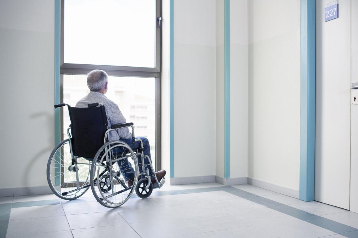 senior in wheelchair looking out of window