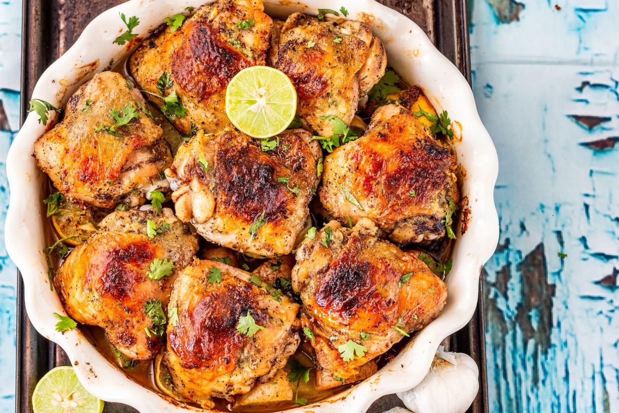 View from top, baked chicken thighs in a white ceramic pot on a rustic, light blue wooden table