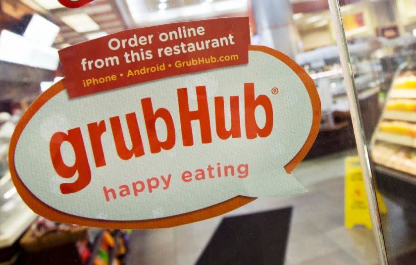 FILE - In this April 4, 2014 file photo, a sign for GrubHub is displayed on the door to a New York restaurant. The owner of KFC and Taco Bell, is teaming up with Grubhub to expand its delivery business. Yum Brands said Thursday, Feb. 8, 2018, that Grubhub will run KFC and Taco Bell delivery and online ordering in the United States. GrubHub will provide delivery people and its technology.(AP Photo/Mark Lennihan, File)