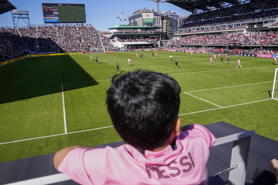 A fan wearing a Lionel Messi jersey watches the second half of an MLS soccer match between DC United and Inter Miami at Audi Field, Saturday, March 16, 2024, in Washington.  (AP Photo/Nathan Howard)