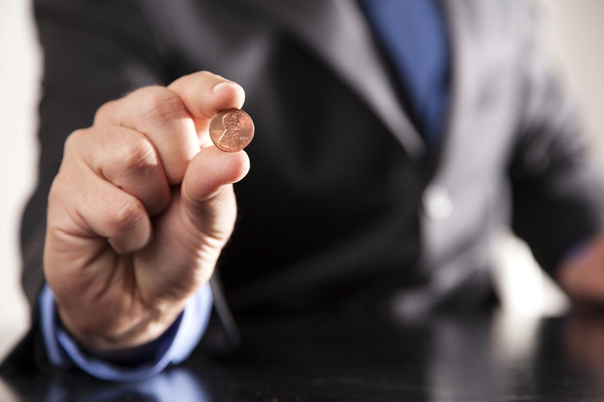 hand holding one penny with man's midsection in background