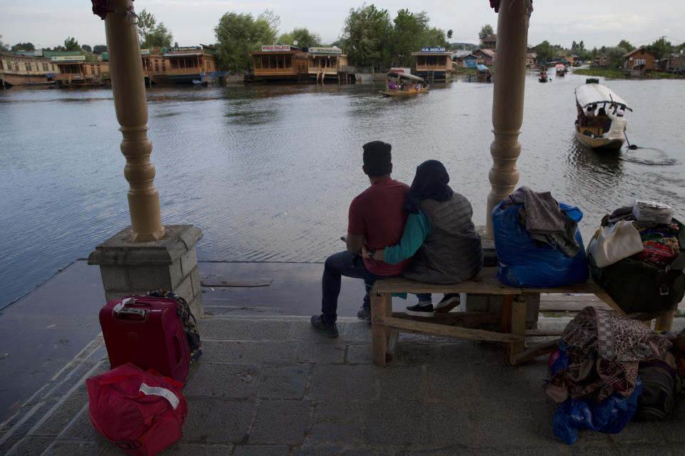 An Indian couple waits for transport as they prepare to leave Srinagar, Indian controlled Kashmir, Saturday, Aug. 3, 2019. Thousands of Indian students and visitors were fleeing Indian-controlled Kashmir on Saturday after the government ordered tourists and Hindu pilgrims visiting a Himalayan cave shrine "to curtail their stay" in the disputed territory, citing security concerns. (AP Photo/ Dar Yasin)