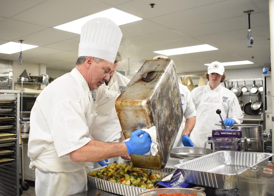 Culinary Program Director Marco Adornetto pours Ratatouille into trays at a previous Ethnic Food Fair at Zane State College while students Branson Umensetter, Anthony Pridgeon and Nickolas Snyder look on.