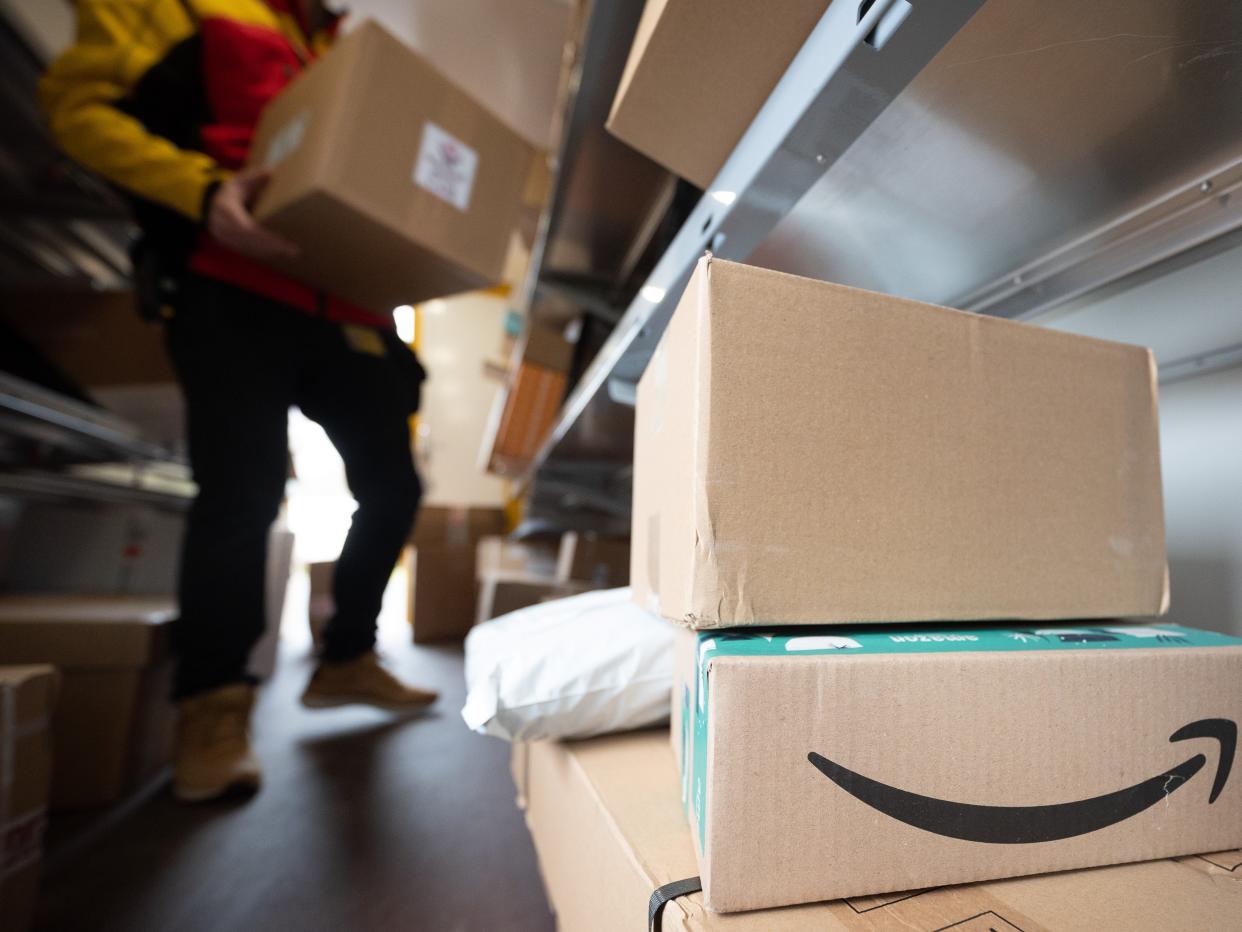 a delivery person carrying boxes with amazon boxes in the foreground